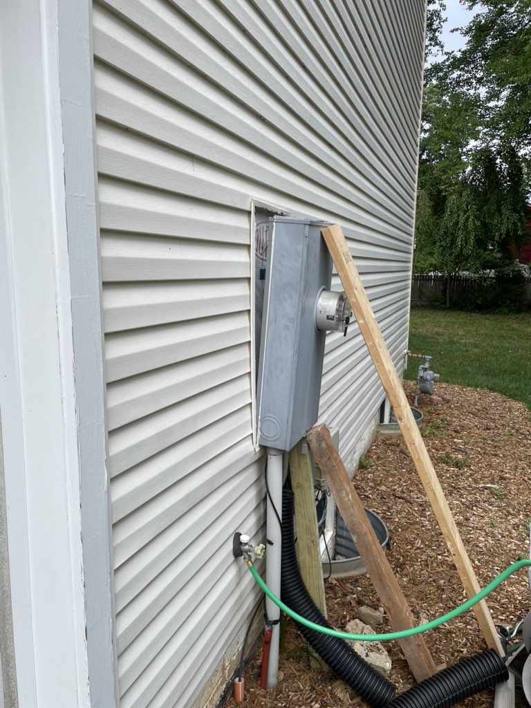 Electric meter base leaning away from a house, braced during repair